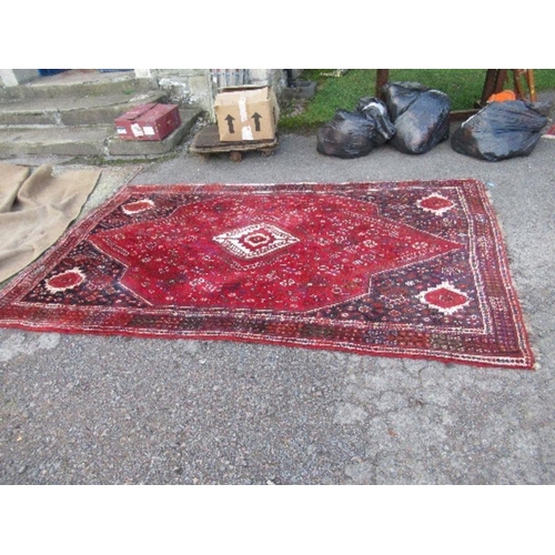 77 - An Eastern design red ground rug, 67ins x 114ins