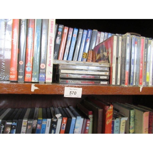 570 - Three shelves of assorted DVDs, CDs, books, and records