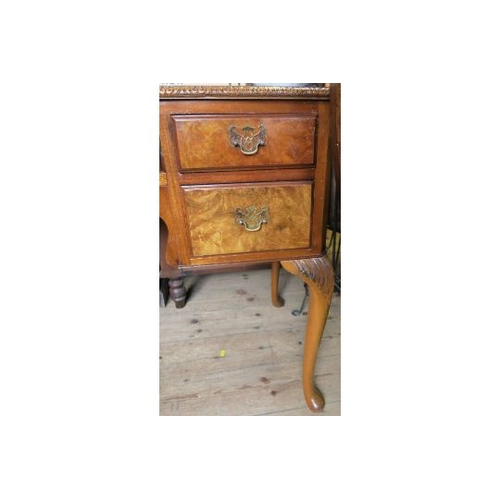 50 - A reproduction walnut writing desk, with leather inset top and carved decoration, having an arrangem... 