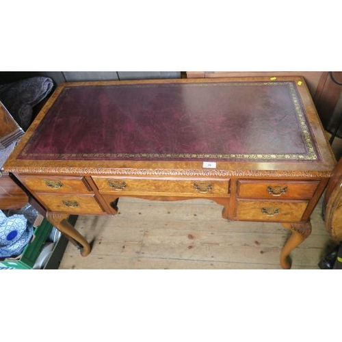 50 - A reproduction walnut writing desk, with leather inset top and carved decoration, having an arrangem... 