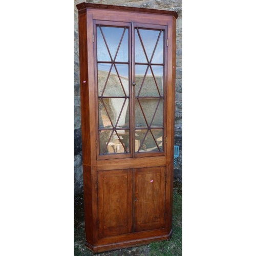 11 - A 19th century mahogany floor standing corner cupboard, the upper section with a pair of glazed door... 