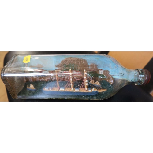 133 - A model ship, in a square shaped bottle, with painted back drop