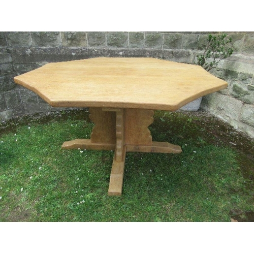 25 - An octagonal oak dining table, with concave borders, raised on cross frame legs, with outswept suppo... 