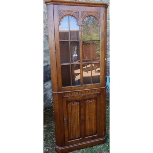 38 - A reproduction oak floor standing corner cupboard, with glazed upper section and cupboard base, havi... 