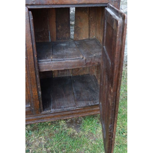 51 - An antique oak duadarn, the upper panelled section fitted with a cupboard, the base with a pair of c... 