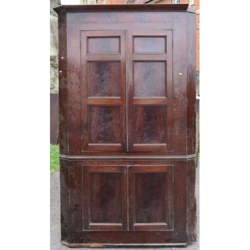 65 - A free standing late Georgian mahogany corner cupboard, of double height, with panelled doors, to up... 