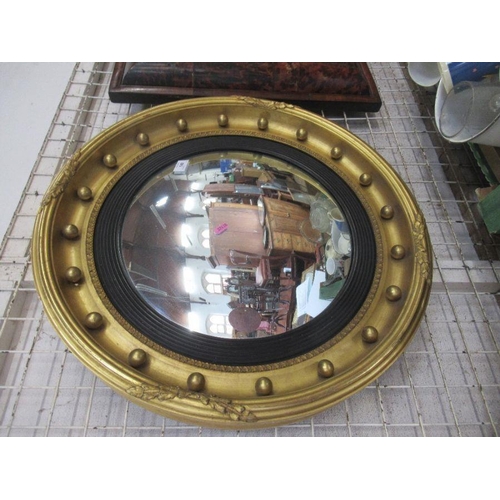 140 - A circular convex wall mirror, the gilt frame with ball decoration and black slip, overall dimension... 