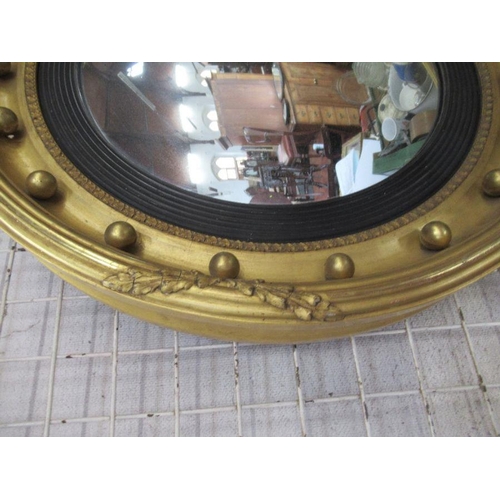 140 - A circular convex wall mirror, the gilt frame with ball decoration and black slip, overall dimension... 