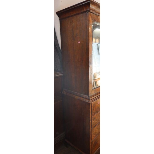 23 - An antique walnut cabinet on chest, the upper section fitted with a pair of mirrored doors, opening ... 