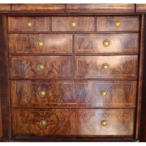 23 - An antique walnut cabinet on chest, the upper section fitted with a pair of mirrored doors, opening ... 