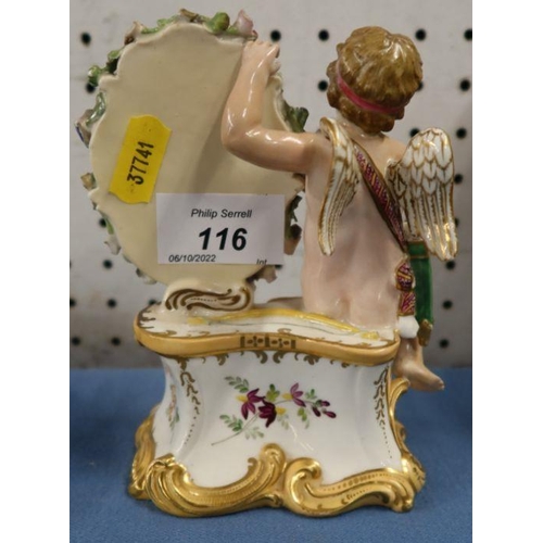 116 - A 19th century porcelain ornament of a seated cherub by an oval floral encrusted plaque decorated wi... 