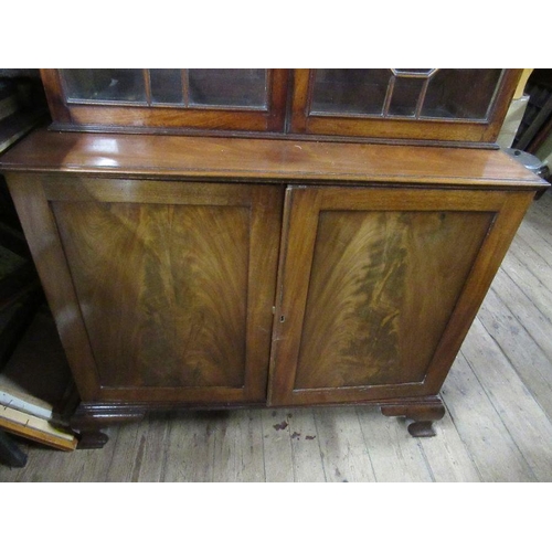 135 - A late Georgian mahogany bookcase cupboard, the upper section fitted with astragal glazed doors open... 