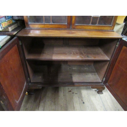 135 - A late Georgian mahogany bookcase cupboard, the upper section fitted with astragal glazed doors open... 