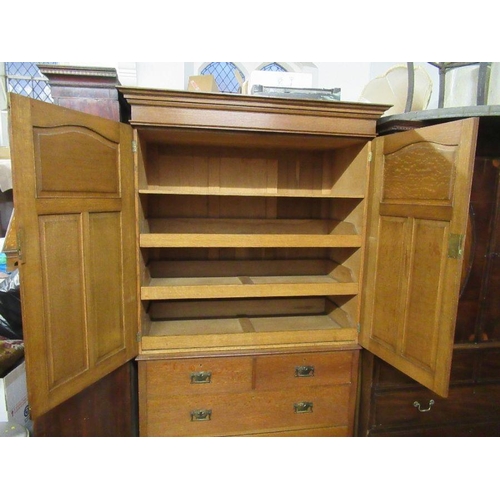 136 - An Arts and Crafts  light oak linen press, the two panel doors opening to reveal slide out trays,ove... 