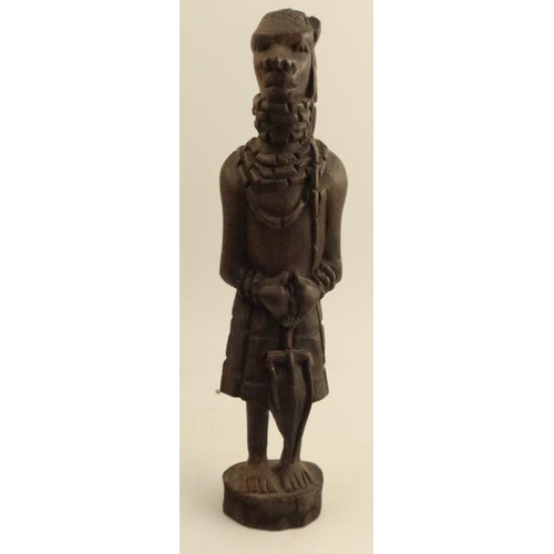 253 - A carved wooden African figure, together with another cast figure holding a shield