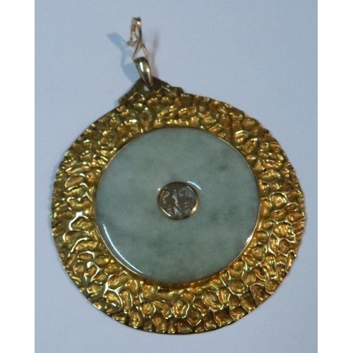 395 - A large jadeite disc pendant, set with characters to the center and mounted in a textured yellow met... 