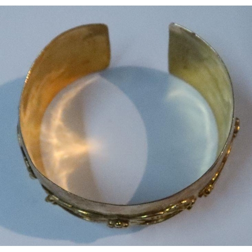 402 - A gold cuff bangle, with stylised raised frieze, 28g