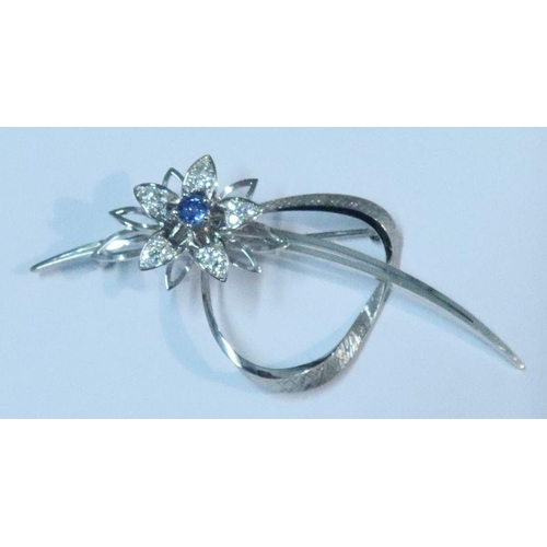 406 - An 18k white gold and floral spray brooch, the flower with central round cut sapphire and three grad... 