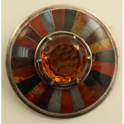 440 - A Scottish silver circular brooch, set with an orange citrine to the centre, surround by panels of a... 