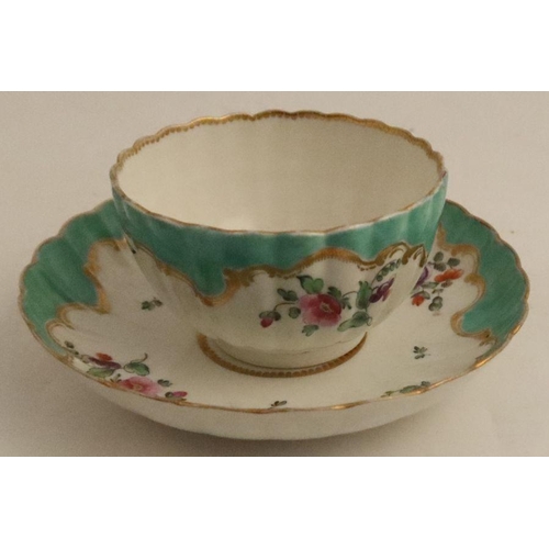 670 - A Worcester tea bowl and saucer, painted in colours with flower sprays to an apple green border