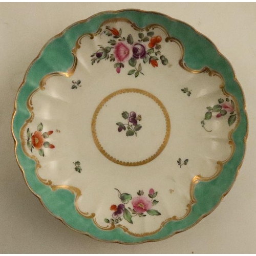 670 - A Worcester tea bowl and saucer, painted in colours with flower sprays to an apple green border