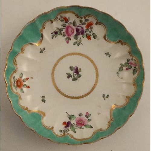 670 - A Worcester tea bowl and saucer, painted in colours with flower sprays to an apple green border