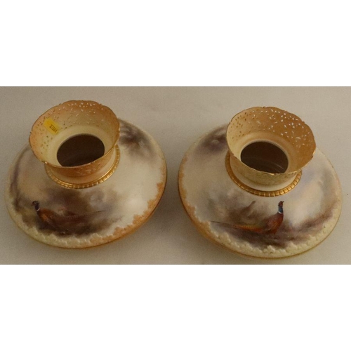 686 - A pair of Royal Worcester blush ivory vases, with pierced necks, the squat body painted with pheasan... 