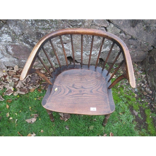 69 - A low stick back armchair, with elm seat and raised on turned legs