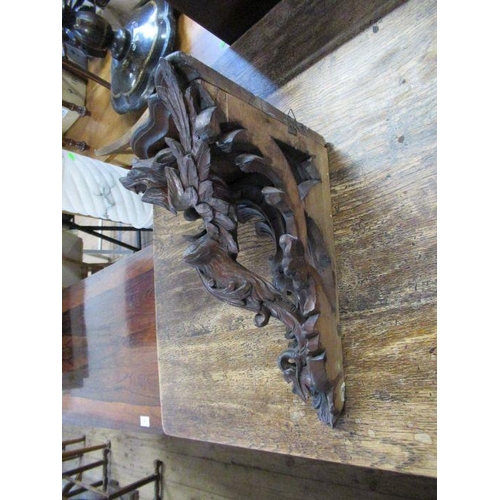 83 - A carved oak corner wall bracket, decorated with a stylised mythical creature, width 16ins