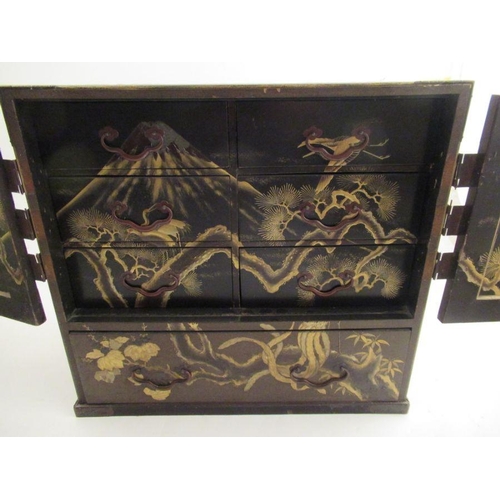 226 - A Japanese table cabinet with gilt chinoiserie decoration, having 2 cupboard doors enclosing draws w... 