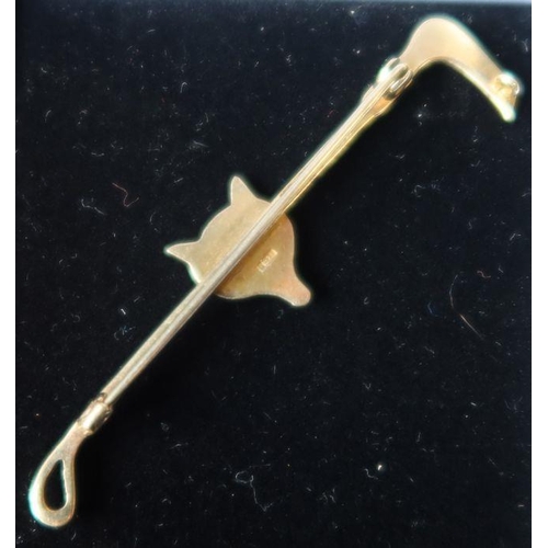 405 - A 9ct gold stock or tie pin, formed as a hunting crops and mounted with a fox mask with ruby eyes, w... 