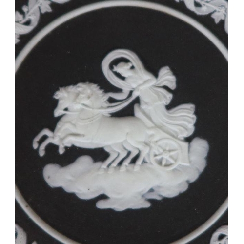 559 - A 19th century Wedgwood black jasperware trophy plate, with a central rounded of Cynisca of Sparta -... 