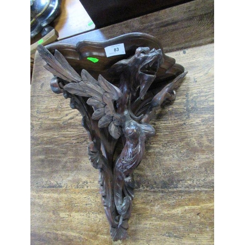 83 - A carved oak corner wall bracket, decorated with a stylised mythical creature, width 16ins