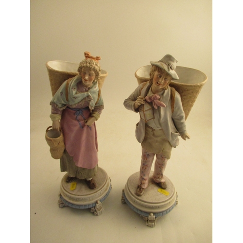 573 - A pair of 19th century continental figures of a man and a lady with baskets,  raised on circular bas... 