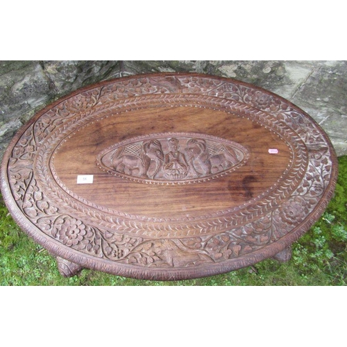 56 - An Eastern design table, with carved decoration all over, raised on 4 legs stylized as elephants, wi... 