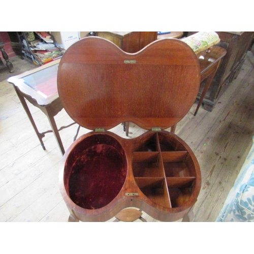 65 - An Edwardian satinwood kidney shaped work table, having a rising lid to reveal fitted compartments, ... 