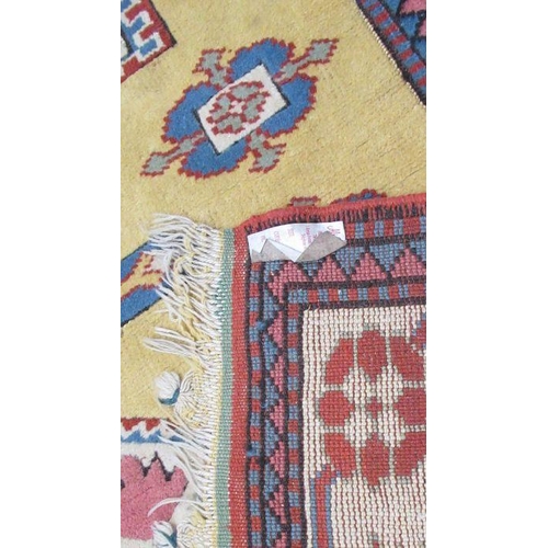 80 - An Eastern style rug, with repeating symbols to a yellow ground, 65ins x 50ins