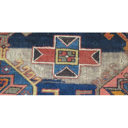 81 - An Eastern design rug, the blue ground field decorated with hooked lozenges, 132ins x 74ins