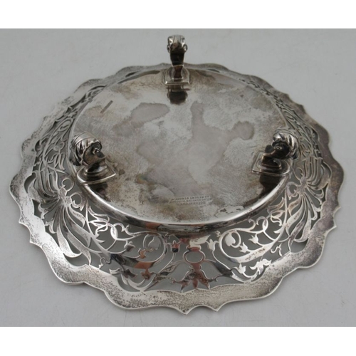 284 - A silver dish, with shaped edge, pierced border and inscription to the center, raised on three knurl... 