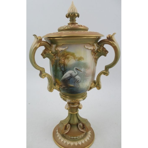 387 - A Royal Worcester after Hadley covered vase, having three handles, decorated with panels of storks b... 