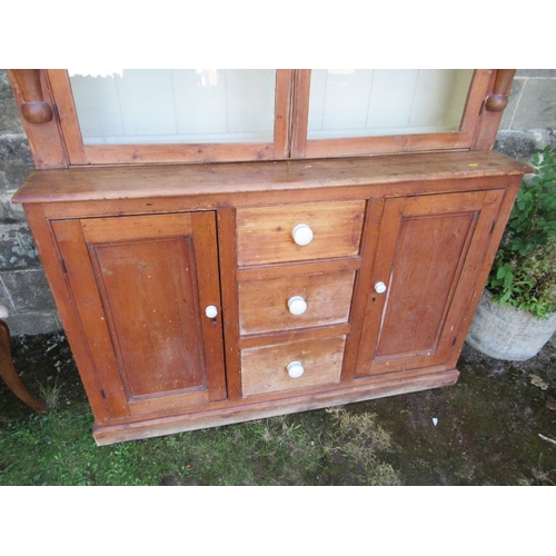 56 - A pine cupboard the upper section having two glazed doors over cupboards and drawers to the base  (2... 