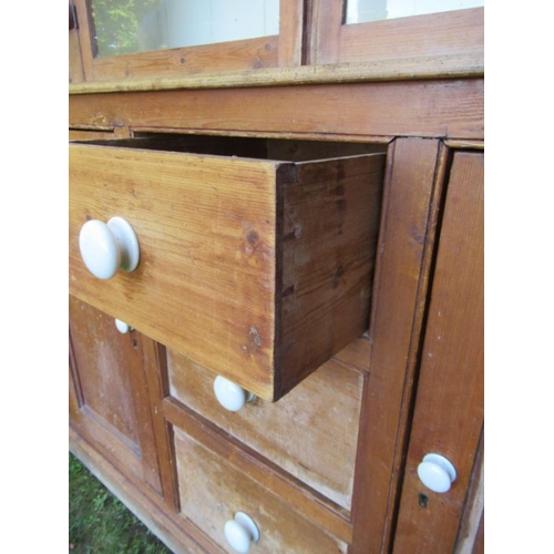 56 - A pine cupboard the upper section having two glazed doors over cupboards and drawers to the base  (2... 