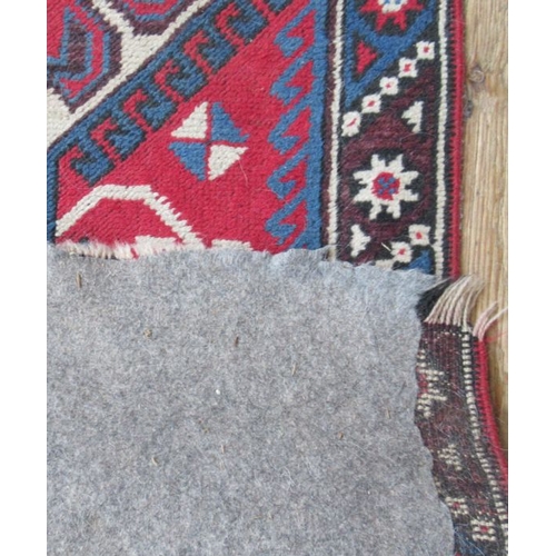 72 - An Eastern design rug, the red ground field having purple ground lozenges, 85ins x 50ins, together w... 