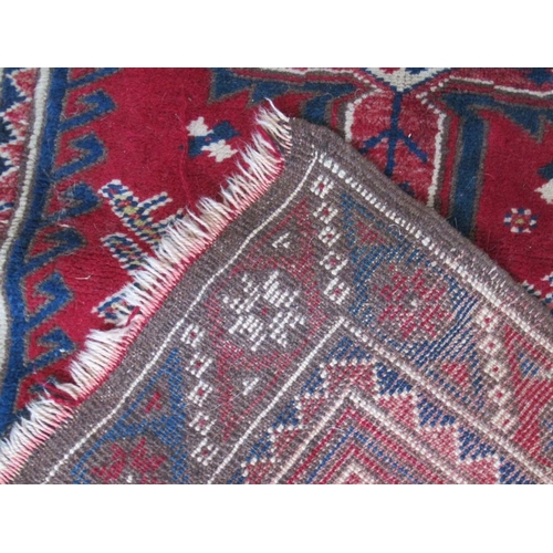 73 - An Eastern design rug, decorated with hooked motifs, in red, blue and white, 53ins x 31ins