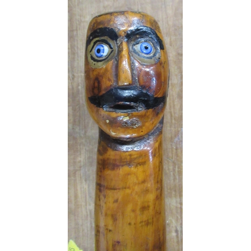 130 - 38576 A carved wooden walking stick, with face pommel, length 34ins