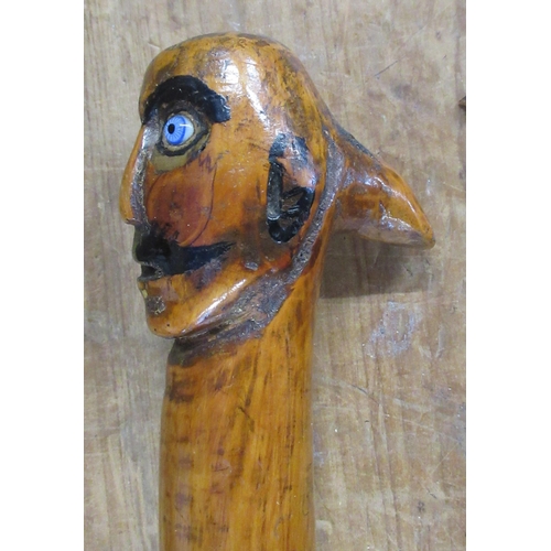 130 - 38576 A carved wooden walking stick, with face pommel, length 34ins