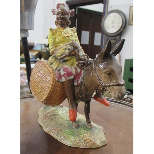 211 - A Beswick figure, Susie Jamaica, holding fruit, sitting astride a donkey with carrying baskets, 1347