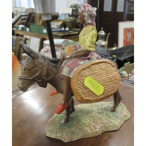 211 - A Beswick figure, Susie Jamaica, holding fruit, sitting astride a donkey with carrying baskets, 1347