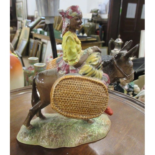 211 - A Beswick figure, Susie Jamaica, holding fruit, sitting astride a donkey with carrying baskets, 1347