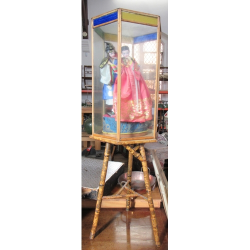 31 - A bamboo hexagonal table, the top with display case containing costume dolls, height 50ins